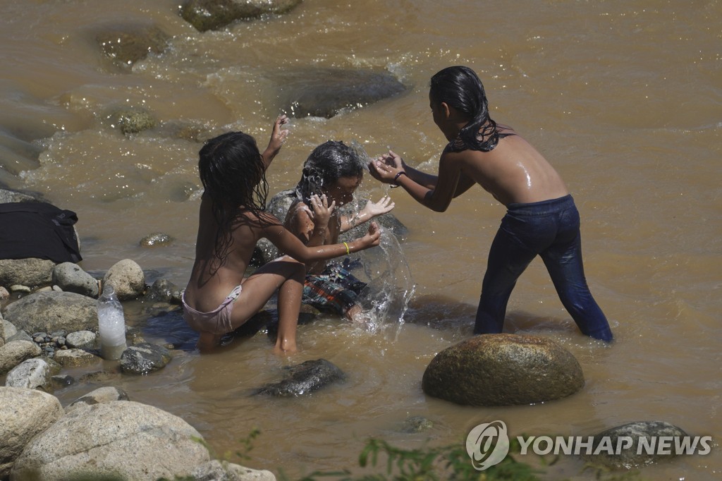 강에서 물장구치는 이민자 아이들
