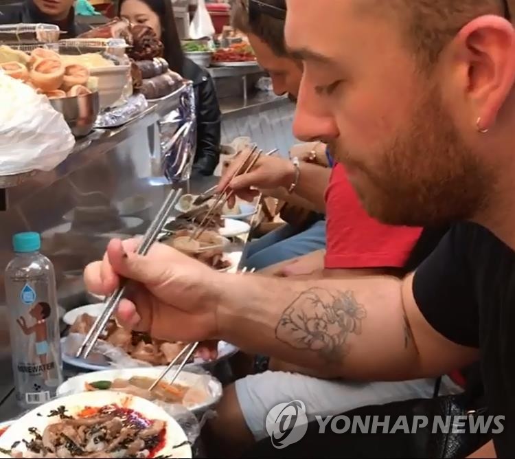１０月に来韓した英国のシンガーソングライター、サム・スミスがソウル市内の市場でサンナクチを食べている（本人のインスタグラムから）＝（聯合ニュース）
