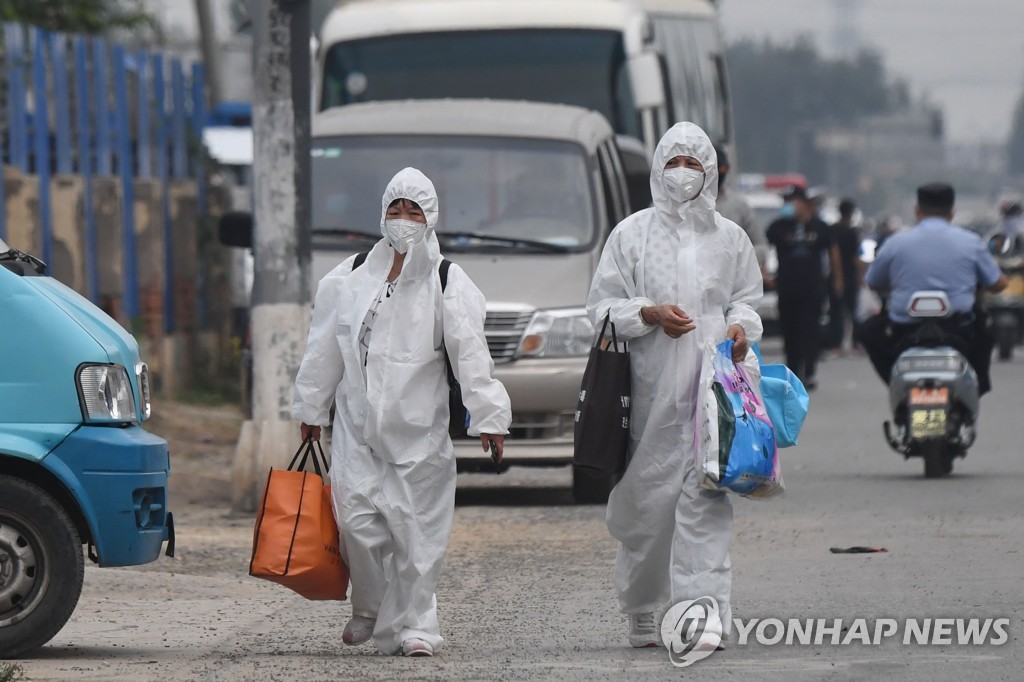 13일 베이징 신파디 시장 부근에서 2명의 여성이 보호복을 입고 걸어가고 있다. [AFP=연합뉴스]