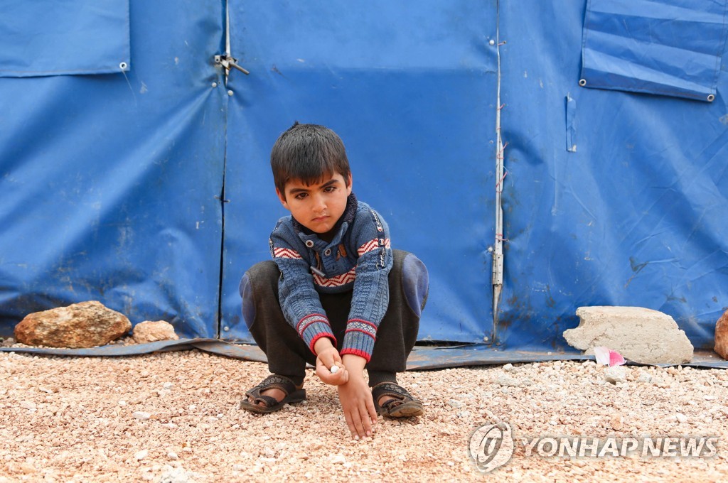 10일(현지시간) 시리아 북부 한 피난처 캠프 바깥에 부모를 잃어버린 한 11살 소년이 앉아있다. 