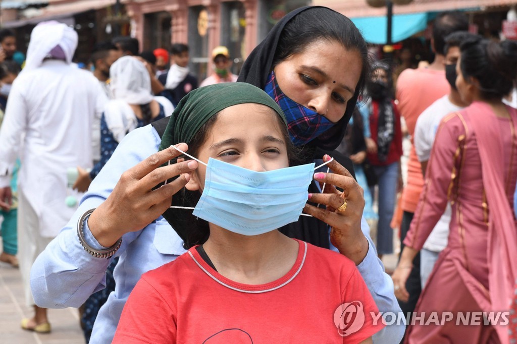 한 여성이 자녀의 얼굴에 마스크를 씌워주고 있다.