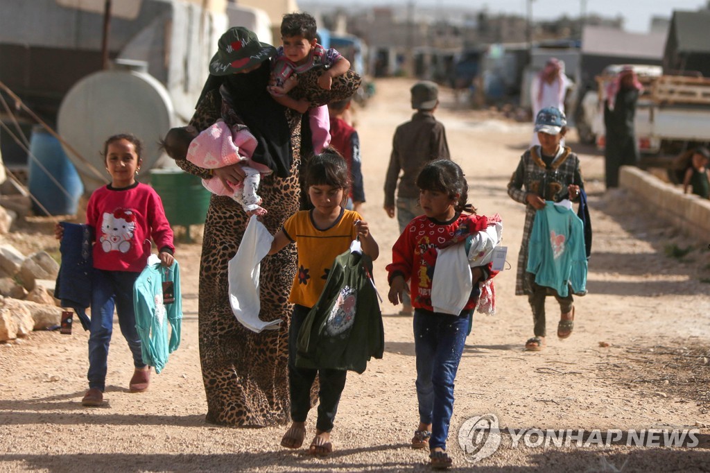 터키 국경 인근의 다나 마을에서 시리아 아이들이 구호품을 받아서 텐트로 향하고 있다. 