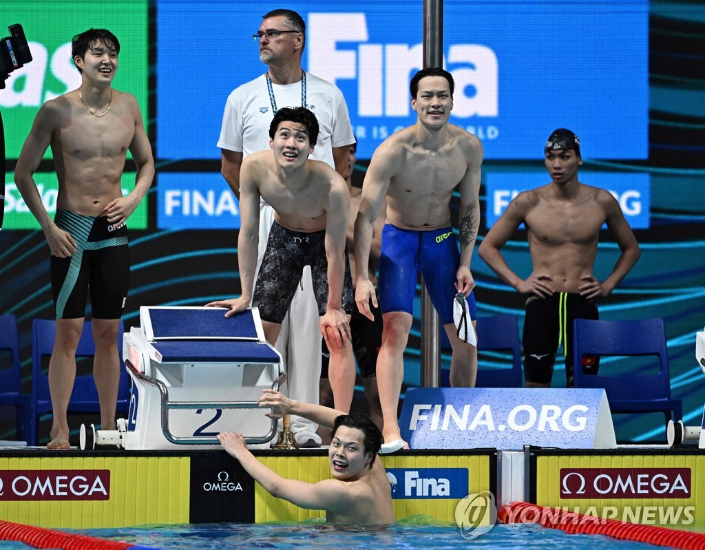 In this AFP photo, South Korean swimmers Hwang Sun-woo, Kim Woo-min and Lee Yoo-yeon (L to R at top) and Lee Ho-joon (in water) check their team's time in the heat for the men's 4x200m freestyle relay during the FINA World Championships at Duna Arena in Budapest on June 23, 2022. (Yonhap)