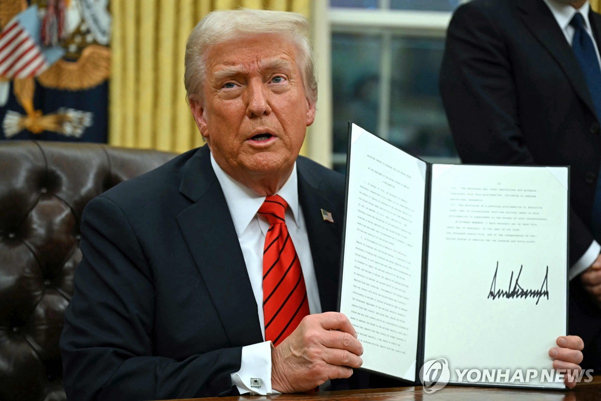 Esta foto, publicada por la AFP, muestra al presidente estadounidense Donald Trump firmando una orden ejecutiva en la Oficina Oval de la Casa Blanca en Washington el 10 de febrero de 2025. (Yonhap)