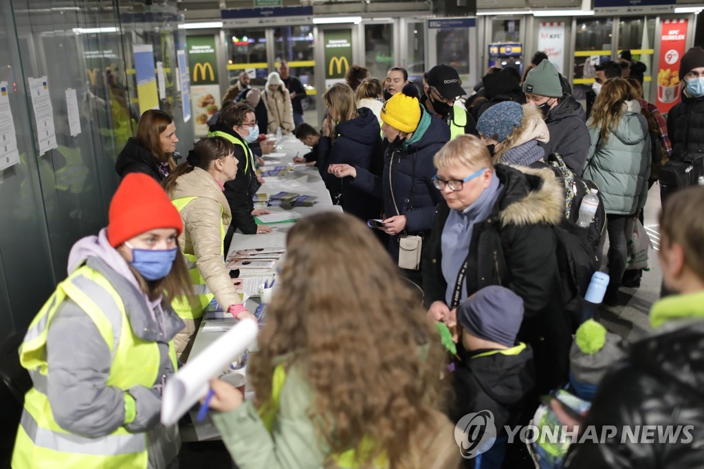 밤 열차로 폴란드에 도착한 우크라이나 피란민들이 특별 설치된 지원 데스크 앞에 서있다. [EPA 연합뉴스 자료사진]