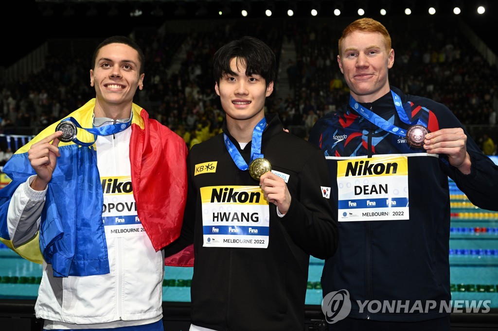 In this EPA photo, Hwang Sun-woo of South Korea (C) holds up his gold medal from the men's 200m freestyle at the FINA Short Course World Swimming Championships at Melbourne Sports and Aquatic Centre in Melbourne on Dec. 18, 2022. Hwang is flanked by the silver medalist, David Popovici of Romania (L), and the bronze medalist, Tom Dean of Britain. (Yonhap)