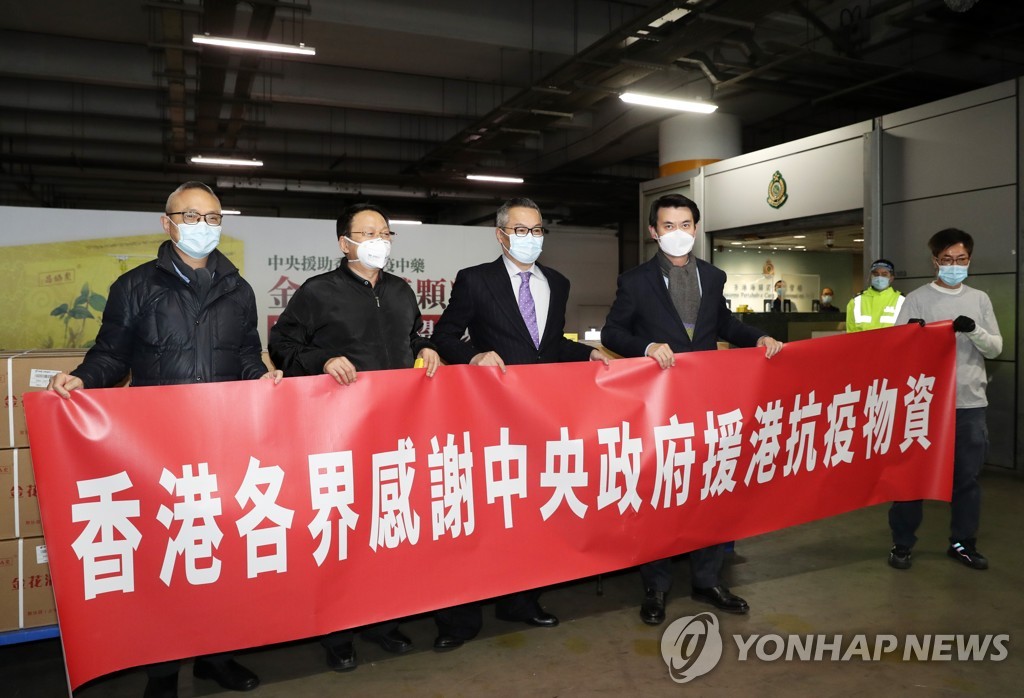 (신화=연합뉴스) 홍콩 관리들이 지난 20일 중국 전통의약품 15만 상자가 홍콩에 도착했음을 알리는 현수막을 들고 있다. 2022.2.21.