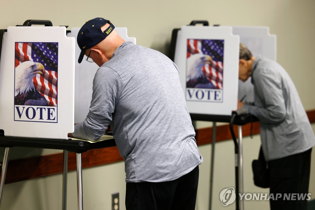 Esta foto, publicada por Reuters, muestra a ciudadanos estadounidenses marcando sus boletas en un sitio de votación anticipada en Greensboro, Carolina del Norte, el 22 de octubre de 2024. (Yonhap)