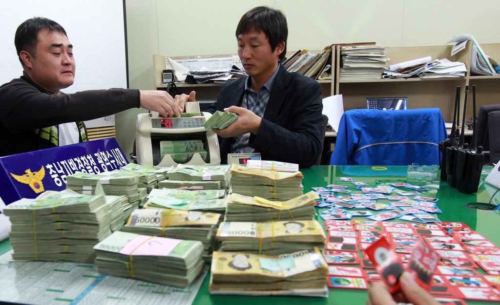 관계자들이 수백억원대의 도박판을 벌인 일당을 구속하고 압수한 판돈을 세고 있다. (자료사진)