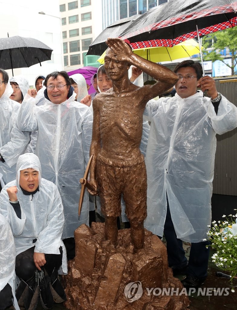 釜山の日本総領事館前で、徴用工像の模型を置き集会を開く市民団体の会員たち＝２４日、釜山（聯合ニュース）
