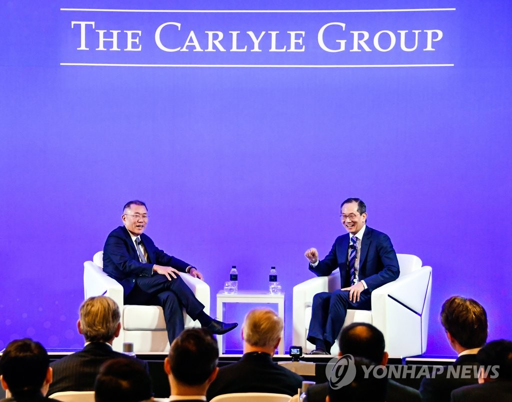 In this photo provided by Hyundai Motor Group on May 23, 2019, Hyundai Motor Group Executive Vice Chairman Chung Eui-sun (L) speaks with Lee Kewsong, Co-Chief Executive Officer of the Carlyle Group, at an event in Seoul. (Yonhap)