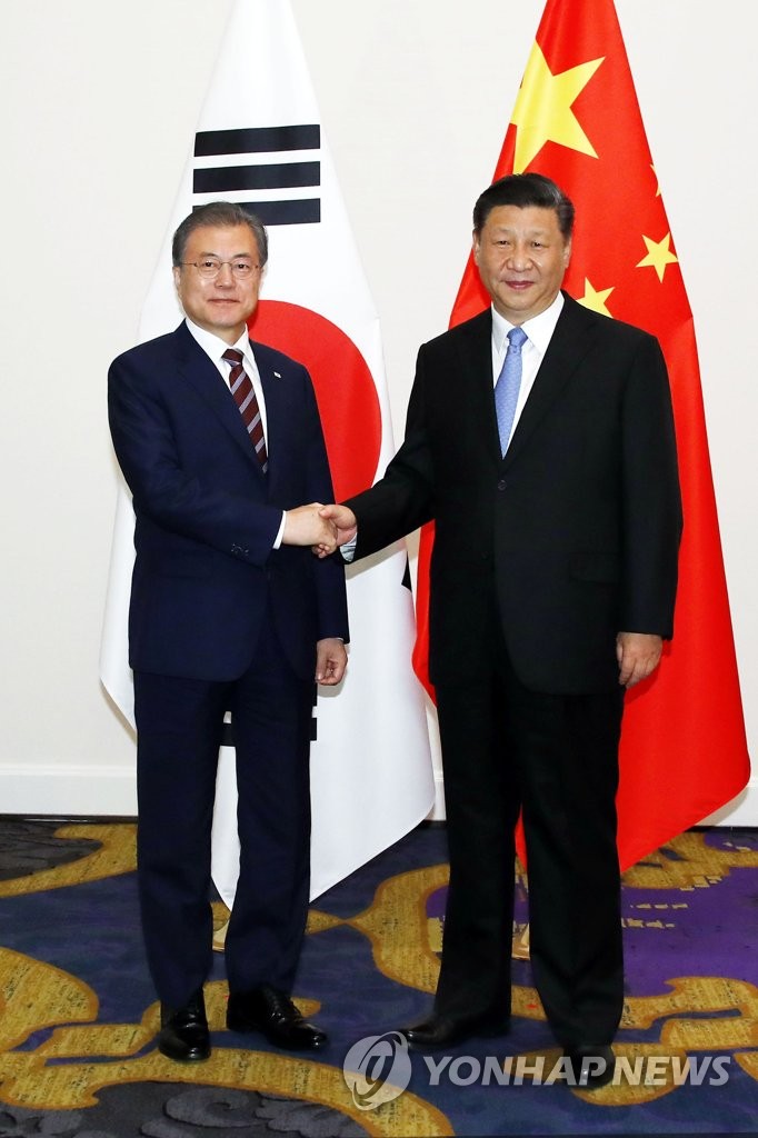 South Korean President Moon Jae-in (L) shakes hands with Chinese President Xi Jinping during a meeting at an Osaka hotel on June 27, 2019. (Yonhap)