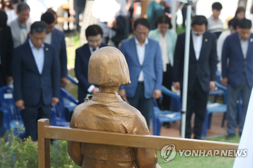 光州で開かれた記念行事で、少女像の前で黙とうする参加者ら＝１４日、光州（聯合ニュース）
