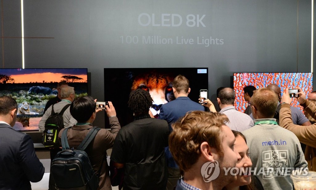 This photo provided by LG Electronics Inc. on Jan. 9, 2020, shows visitors taking photos of LG's OLED TVs displayed at its Consumer Electronics Show (CES) booth in Las Vegas, Nevada. (PHOTO NOT FOR SALE) (Yonhap)