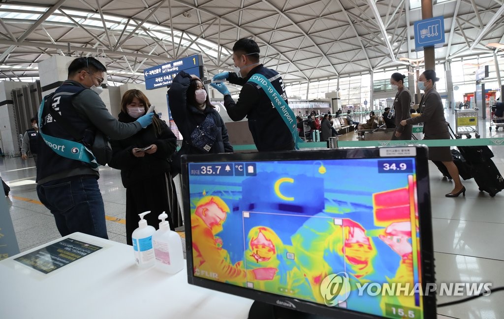 Passengers at Incheon International Airport in Incheon, just west of Seoul, are checked for fever on March 6, 2020. (Yonhap)