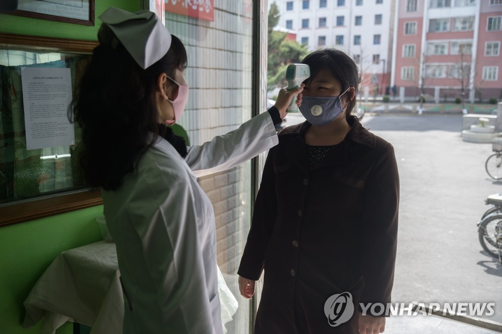 北朝鮮・平壌市内の病院の入り口で、看護師が来院者の体温を確認している＝（ＡＦＰ＝聯合ニュース）