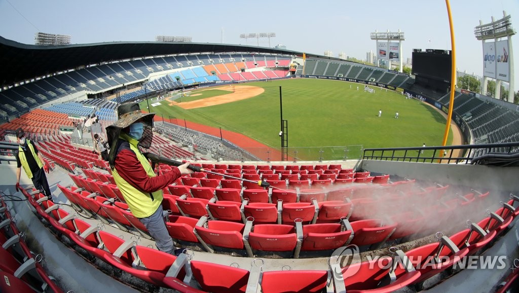 Workers spray disinfectant on seats at Jamsil Baseball Stadium in Seoul on May 1, 2020, four days ahead of the opening of the baseball season. The season will run without spectators in an effort to contain the coronavirus pandemic. (Yonhap)