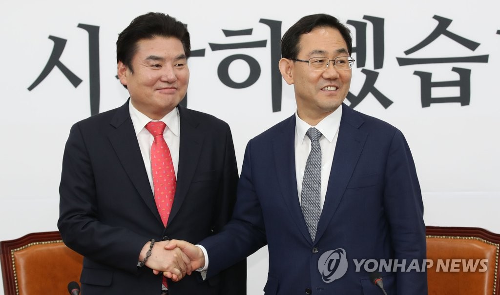 Rep. Joo Ho-young (R), floor leader of the main opposition United Future Party (UFP), shakes hands with Rep. Won Yoo-chul, chief of the UFP's sister Korea Future Party, during a press conference on their merger at the National Assembly in Seoul on May 14, 2020. (Yonhap)