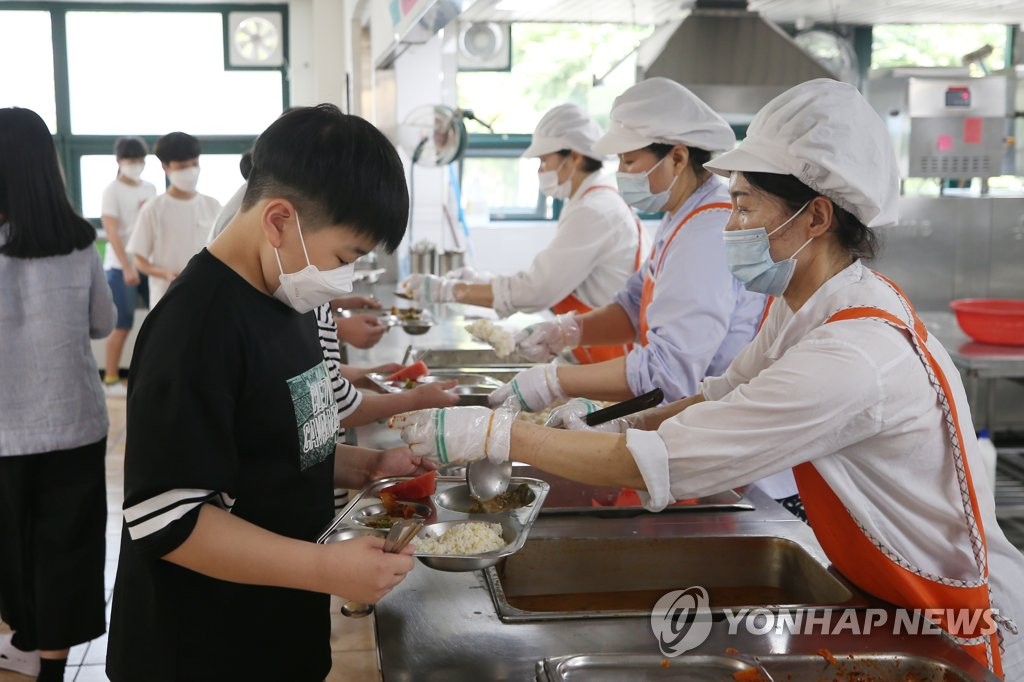 Students receive their lunch while wearing protective masks at an elementary school in Gwangju, 330 kilometers south of Seoul, on June 8, 2020. (Yonhap)