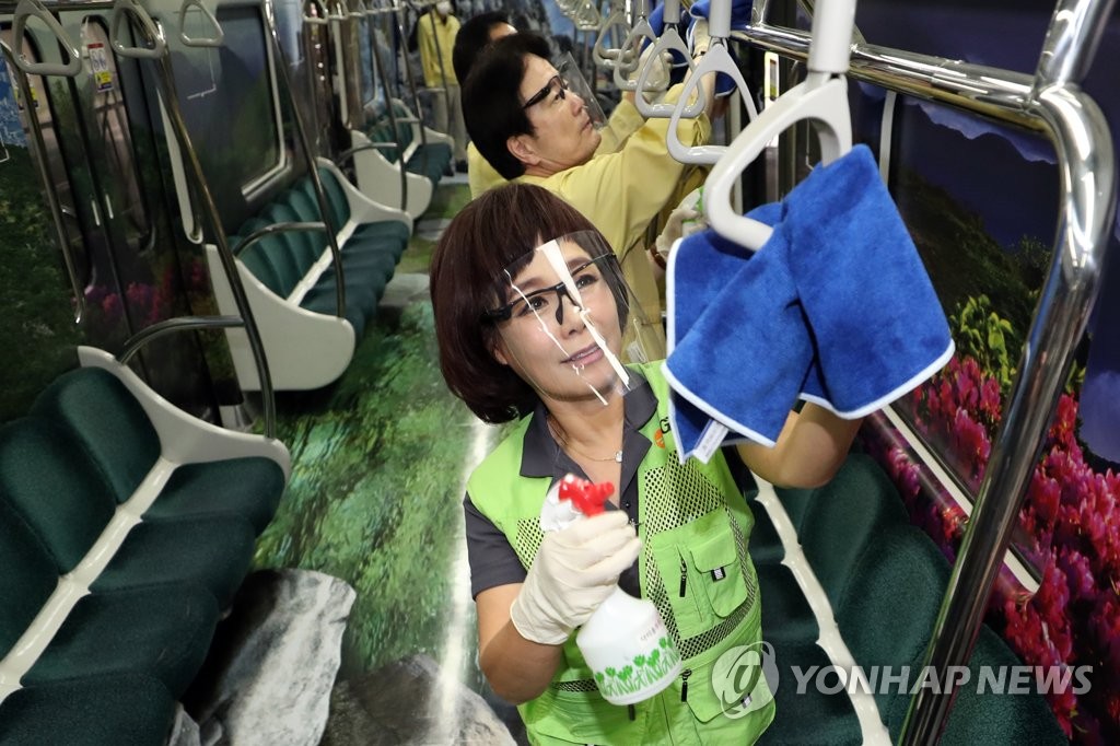 Volunteer workers disinfect hand straps on a subway in Gwangju, 320 kilometers south of Seoul, on Sept. 10, 2020. (Yonhap)
