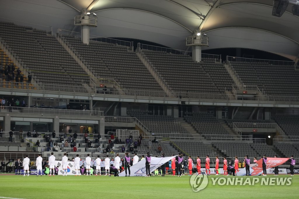 Players for the South Korean men's under-23 national football team (in white) and senior national team stand for the national anthem before their exhibition match at an empty Goyang Stadium in Goyang, Gyeonggi Province, on Oct. 9, 2020. (Yonhap)