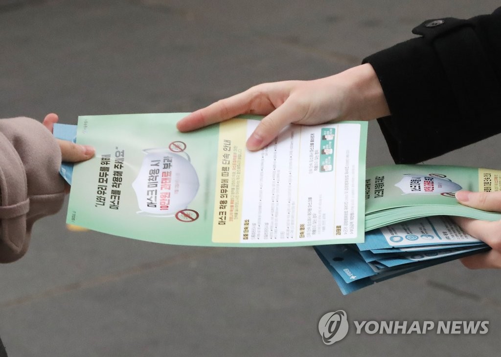 A Seoul city official hands out a flier explaining the enforcement of a new law that will fine people who are not wearing a face mask, in downtown Seoul on Nov. 13, 2020. (Yonhap)