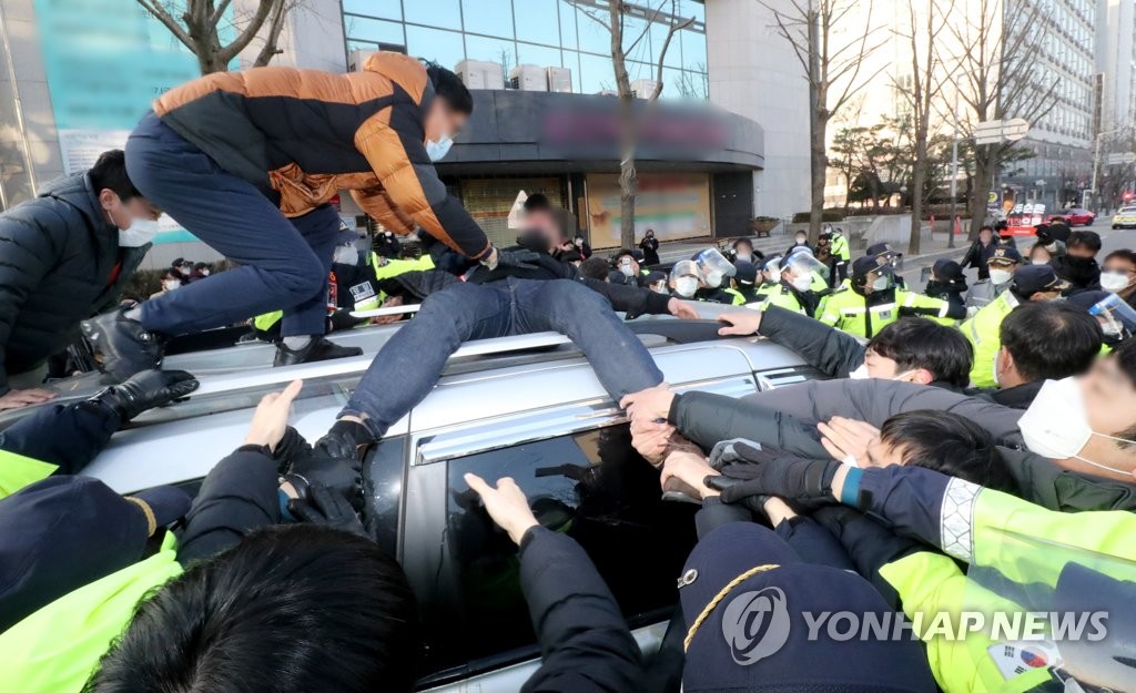 Citizens block a vehicle carrying Cho Doo-soon, one of the country's most notorious child rapists in recent memory, as he leaves a probation facility in Ansan, south of Seoul, on Dec. 12, 2020, following his release from prison. (Yonhap)
