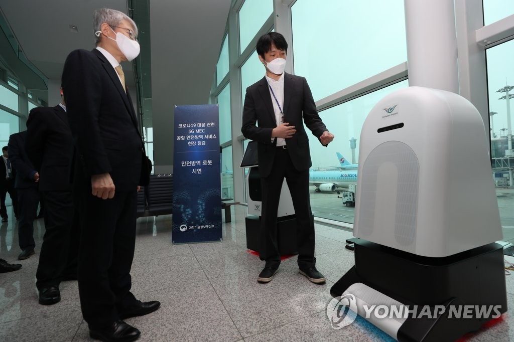 Science and ICT Minister Choi Ki-young (L) looks at a disinfection robot installed at Incheon International Airport, west of Seoul, to prevent the spread of the new coronavirus on Dec. 23, 2020, in this photo provided by the ministry. (PHOTO NOT FOR SALE) (Yonhap)