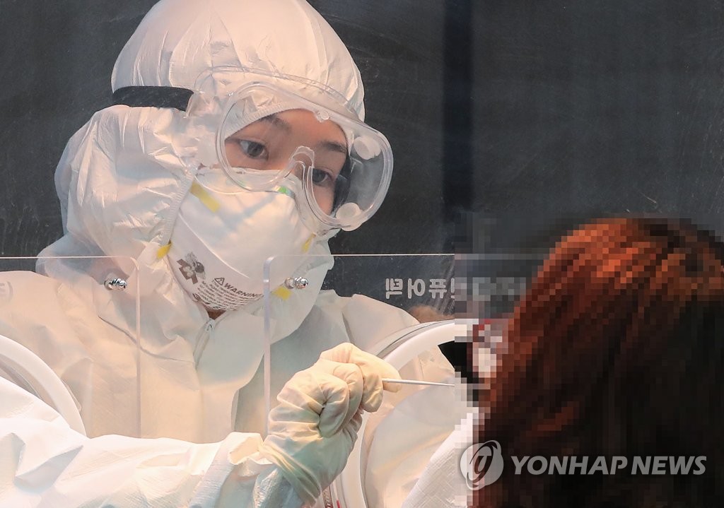 A health worker clad in a protective suit collects a sample from a citizen at a makeshift virus testing clinic in Seoul on Jan. 21, 2021. (Yonhap) 