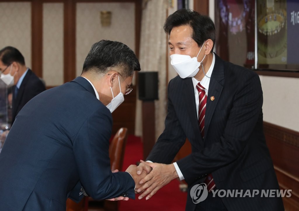 Seoul Mayor Oh Se-hoon shakes hands with Defense Minister Suh Wook before the start of a Cabinet meeting at the government complex in Seoul on April 13, 2021. (Yonhap)