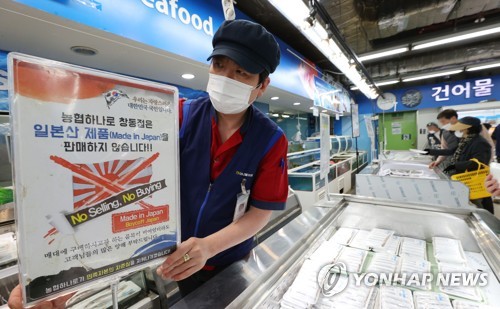 「日本産水産物は販売しません」と書かれた案内文を出すソウル市内のスーパーの関係者＝１３日、ソウル（聯合ニュース）