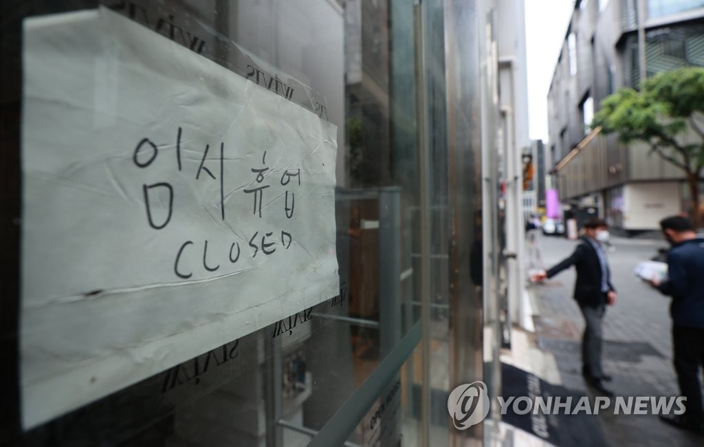 This file photo, taken on May 21, 2021, shows a sign put up at a store in Seoul's shopping district of Myeongdong about a temporary closure over the pandemic. (Yonhap) 