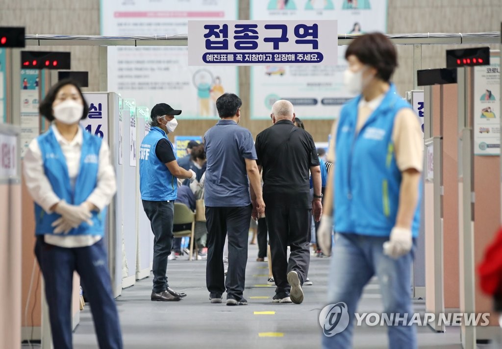 Des travailleurs sanitaires portant un masque guident des citoyens dans un centre d'inoculation vaccinale à Séoul le lundi 7 juin 2021.