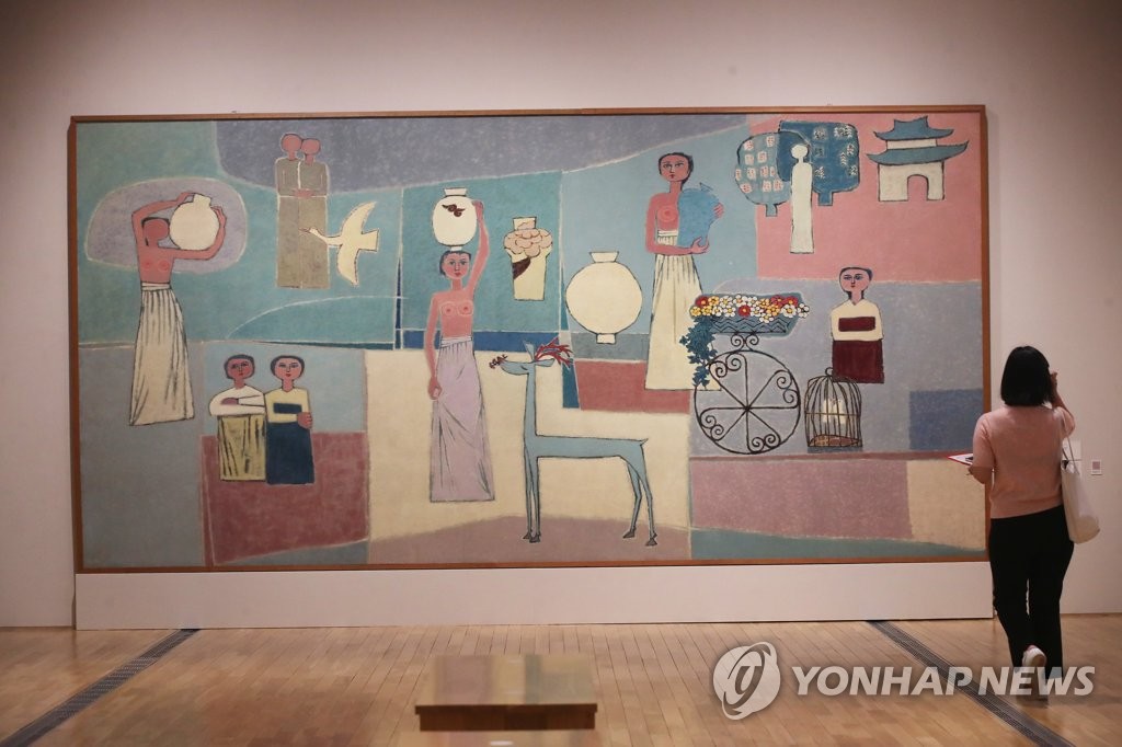 In this file photo, a reporter looks at "Women and Jars" by late Korean painter Kim Whan-ki during a press preview of a special exhibition of late Samsung Group Chairman Lee Kun-hee's art collection at the National Museum of Modern and Contemporary Art in Seoul on July 20, 2021. (Yonhap)