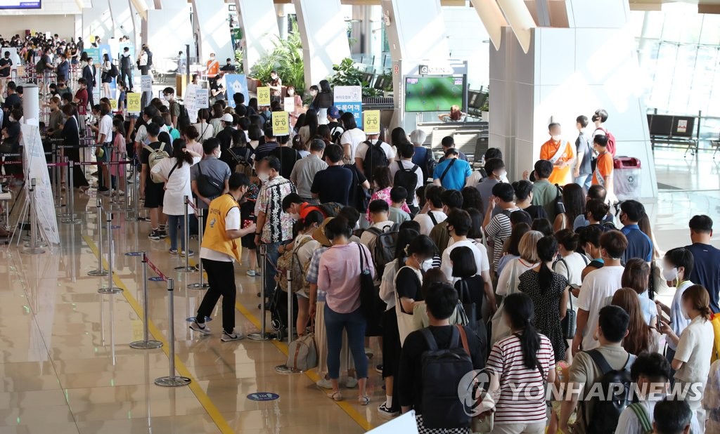 夏休みシーズンに入り、金浦空港は旅行に出掛ける人たちで混雑している＝２２日、ソウル（聯合ニュース）