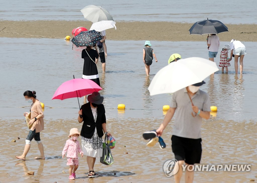Masked visitors walk along a beach in Incheon, west of Seoul, on Aug. 3, 2021. (Yonhap)