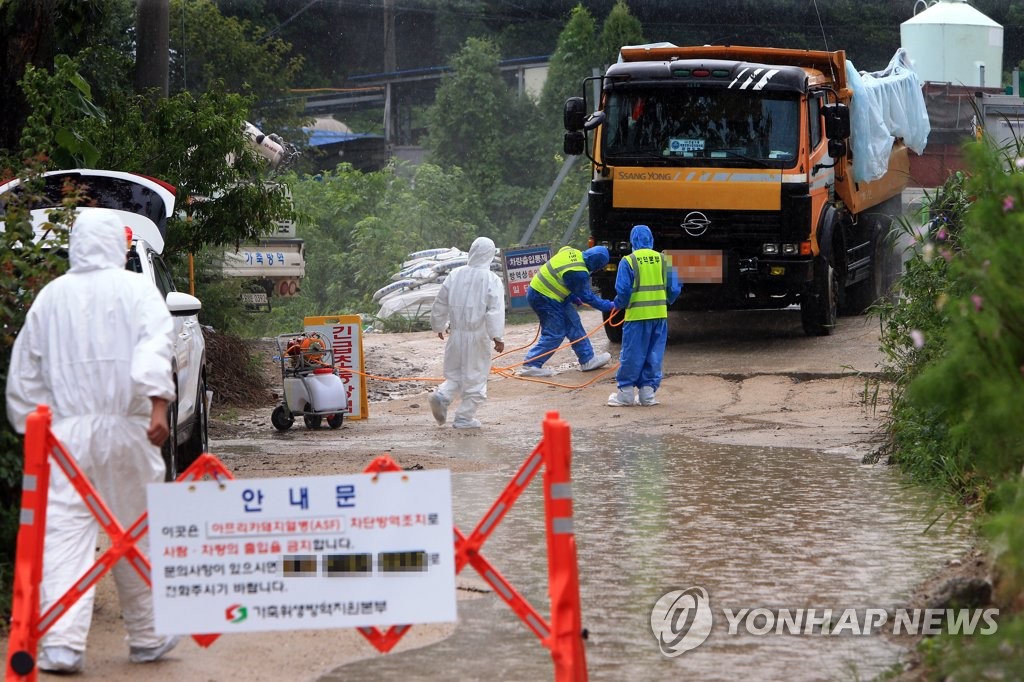 Officials disinfect vehicles entering a pig farm infected with the African swine fever in Goseong, 466 kilometers northeast of Seoul, on Aug. 8, 2021. (Yonhap)