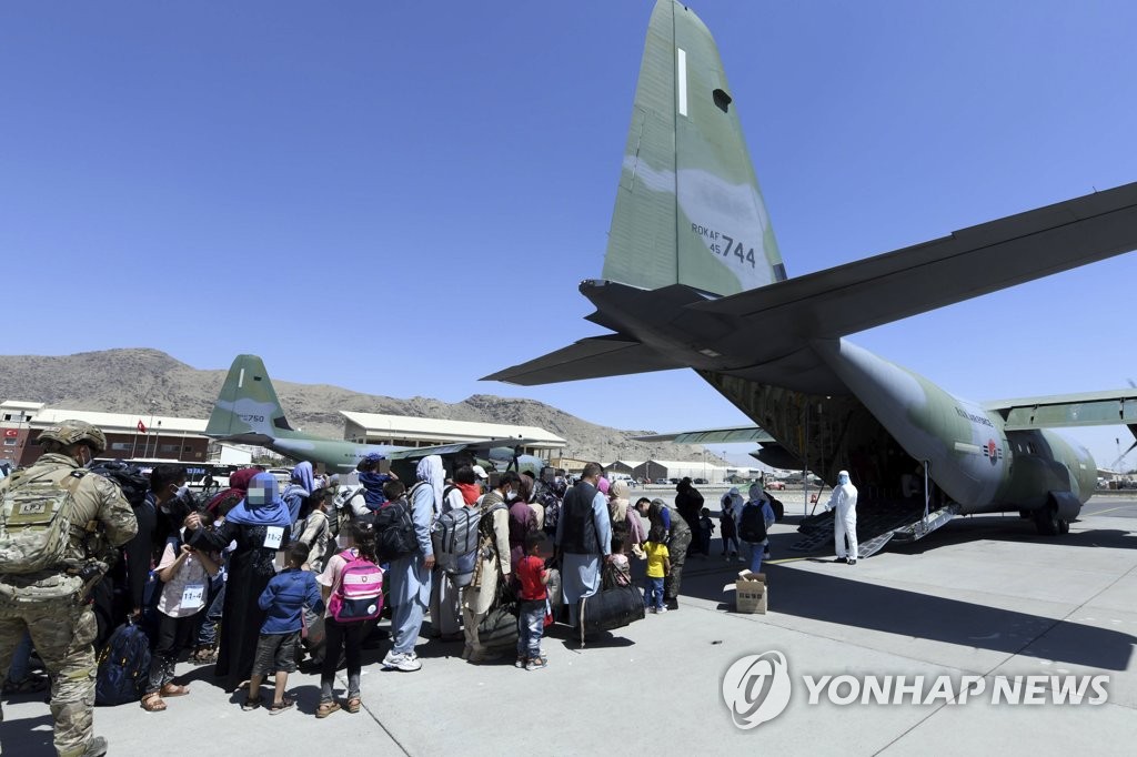 Afghan co-workers and their families board a C-130J plane of the South Korean Air Force at an airport in Kabul during an evacuation operation to bring to the South a total of 391 Afghans from the war-torn country, in this photo provided by the Air Force on Aug. 26, 2021. (PHOTO NOT FOR SALE) (Yonhap) 