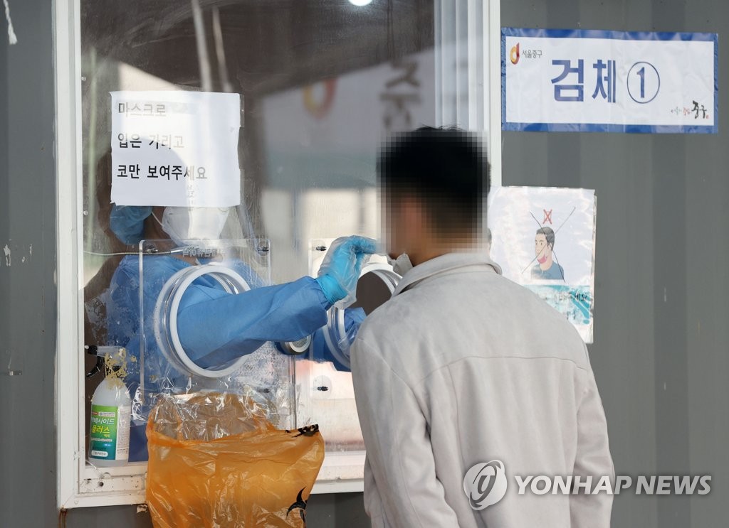 A health worker conducts a COVID-19 test on a citizen at a testing center set up in front of Seoul Station in central Seoul. (Yonhap)
