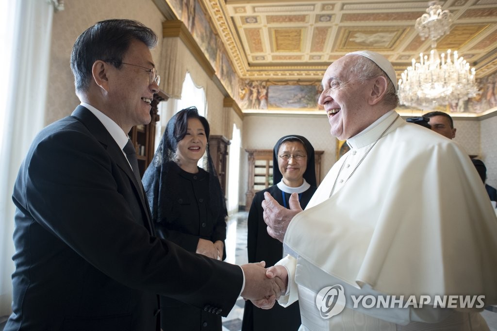 President Moon Jae-in (L) shakes hands with Pope Francis as first lady Kim Jung-sook (2nd from L) watches, before their talks at the Vatican on Oct. 29, 2021, in this photo provided by the Vatican. (PHOTO NOT FOR SALE) (Yonhap)