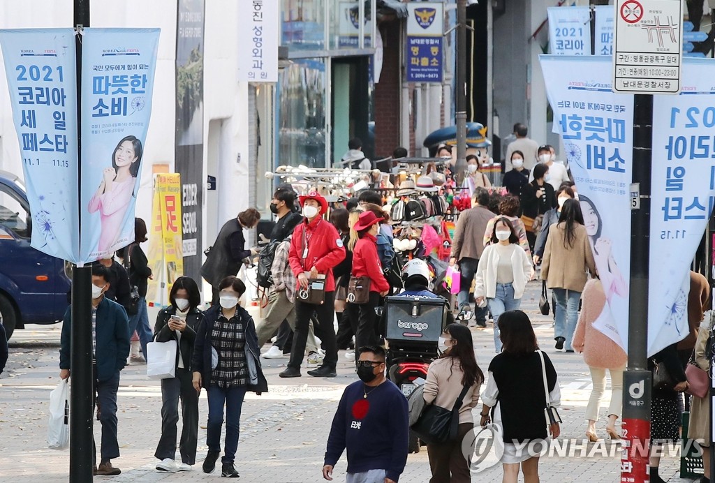 Des personnes marchent dans une rue du quartier commerçant de Myeongdong le dimanche 7 novembre 2021. 