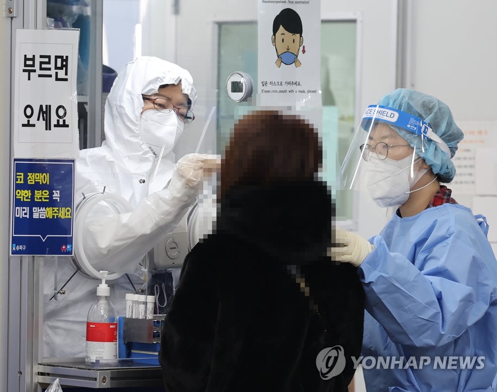 ソウル市松坡区の保健所内の新型コロナ専用診療所で、市民が検体の採取を受けている＝１５日、ソウル（聯合ニュース）