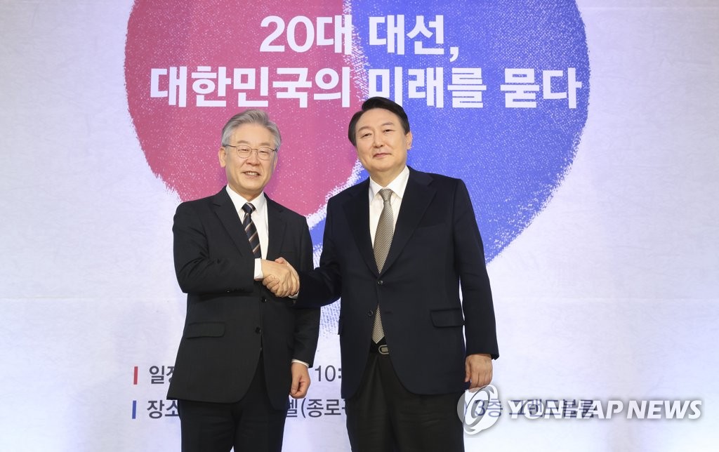 Democratic Party presidential nominee Lee Jae-myung (L) and main opposition People Power Party candidate Yoon Seok-youl shake hands before the start of a forum on the 2021 presidential election held in Seoul on Nov. 24, 2021. (Pool photo) (Yonhap)