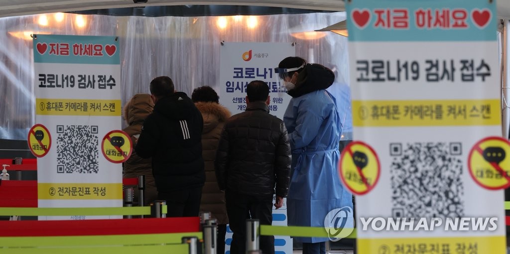 A medical worker guides people standing in line to take coronavirus tests at a screening clinic in front of Seoul Station on Jan. 5, 2022. (Yonhap)
