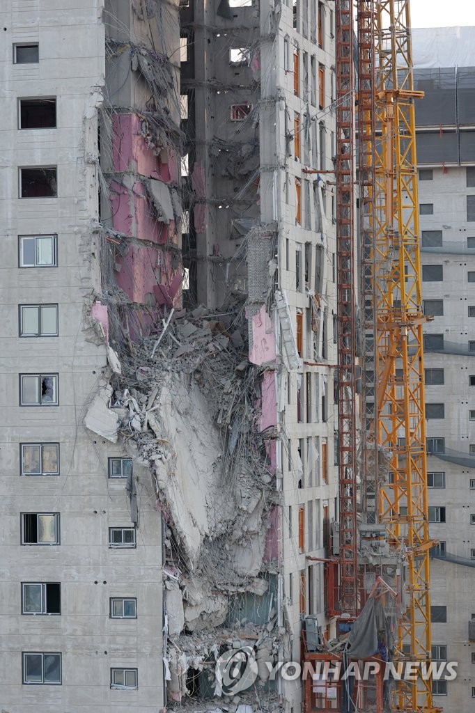 Des débris pendent de l'immeuble d'habitation en construction dans le quartier de Hwajeong à Gwangju, situé dans le sud-ouest du pays. L'opération de secours se poursuit le samedi 15 janvier 2022 pour chercher les cinq disparus. Une personne disparue a été retrouvée hier sans vie. 