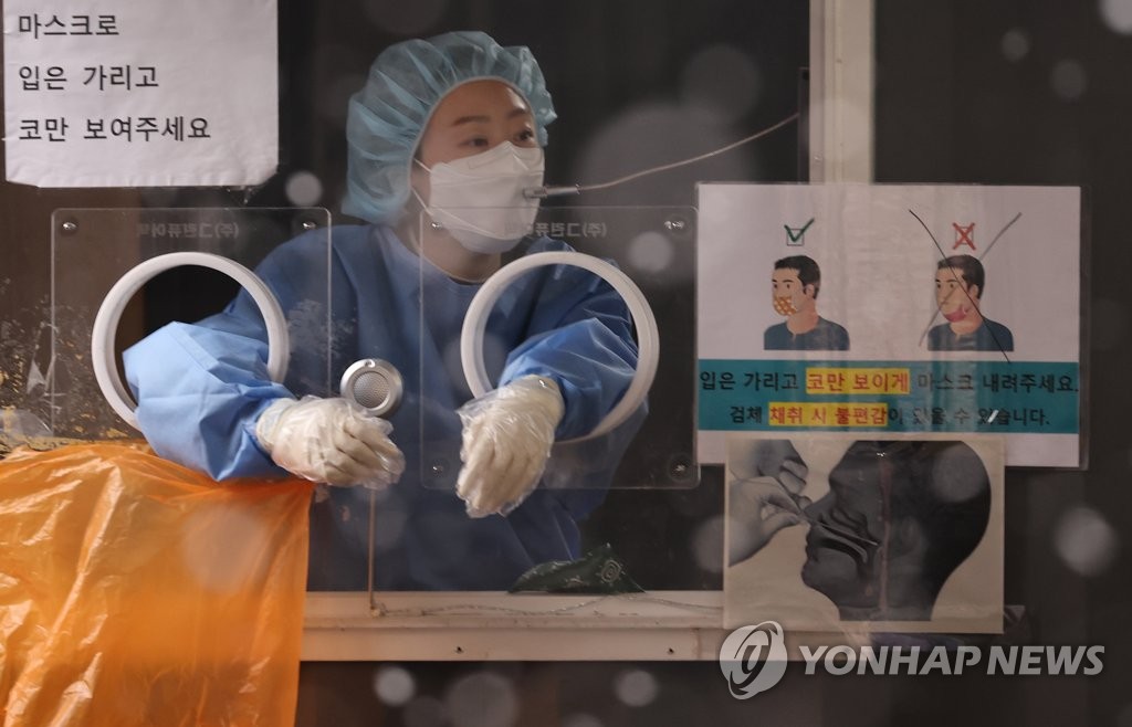 Une membre du personnel médical appelle une personne attendant de passer un test de dépistage du nouveau coronavirus (Covid-19) dans un centre provisoire installé devant la gare de Séoul, le 19 janvier 2022.