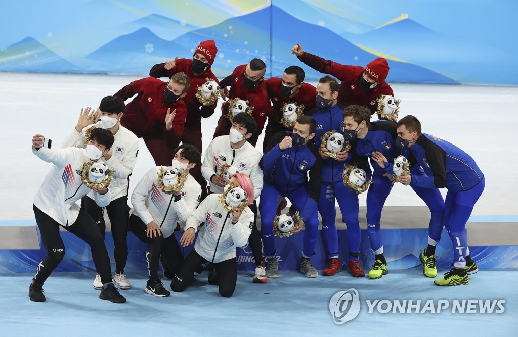 Members of the South Korean men's 5,000m short track relay team (in white) take a selfie with Team Canada (C) and Team Italy after their victory ceremony during the Beijing Winter Olympics at Capital Indoor Stadium in Beijing on Feb. 16, 2022. (Yonhap)