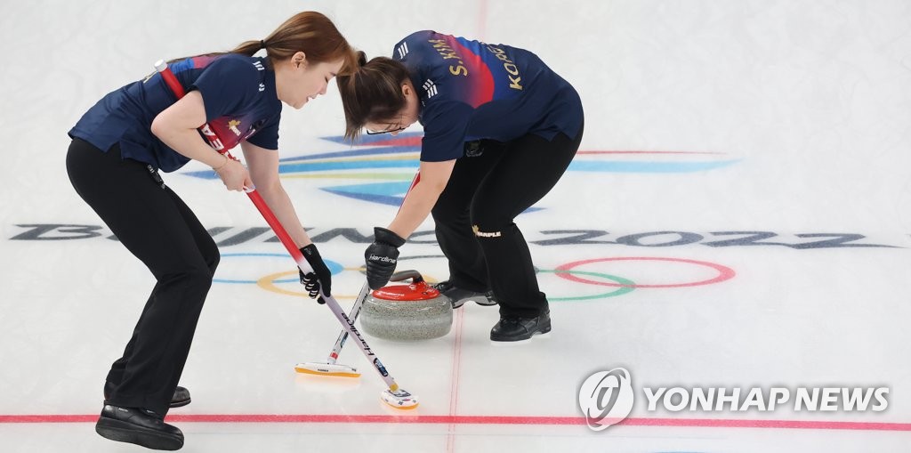 Les curleuses sud-coréennes Kim Cho-hi (à gauche) et Kim Seon-yeong balayent la glace lors d'un match de curling féminin du tournoi toutes rondes contre la Suède aux Jeux olympiques d'hiver de Pékin 2022 au Centre aquatique national de Pékin, le jeudi 17 février 2022.