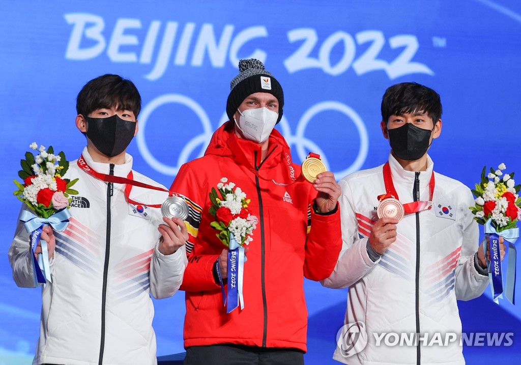South Korean silver medalist Chung Jae-won (L) and bronze medalist Lee Seung-hoon (R) flank the champion, Bart Swings of Belgium, during the medal ceremony for the men's mass start speed skating race at the Beijing Winter Olympics at Beijing Medal Plaza in Beijing on Feb. 19, 2022. (Yonhap)