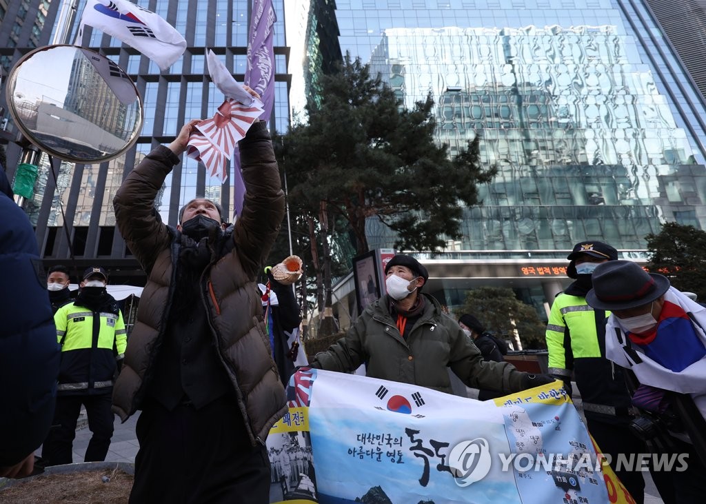 旭日旗が描かれた紙を破る市民団体の関係者＝２２日、ソウル（聯合ニュース）